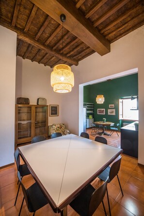A dining area with a large table, chairs, and a hanging light fixture.