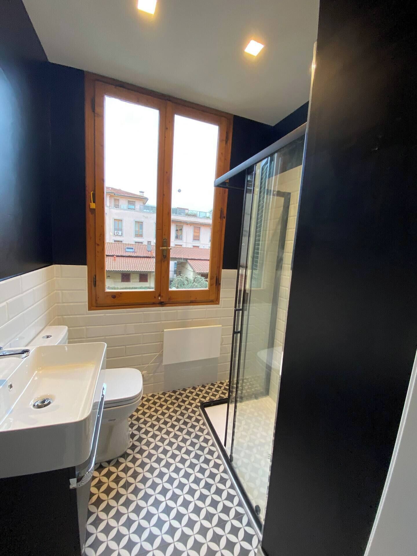 Ein modernes Badezimmer mit einem großen Fenster, einer Dusche und einem Waschbecken.
