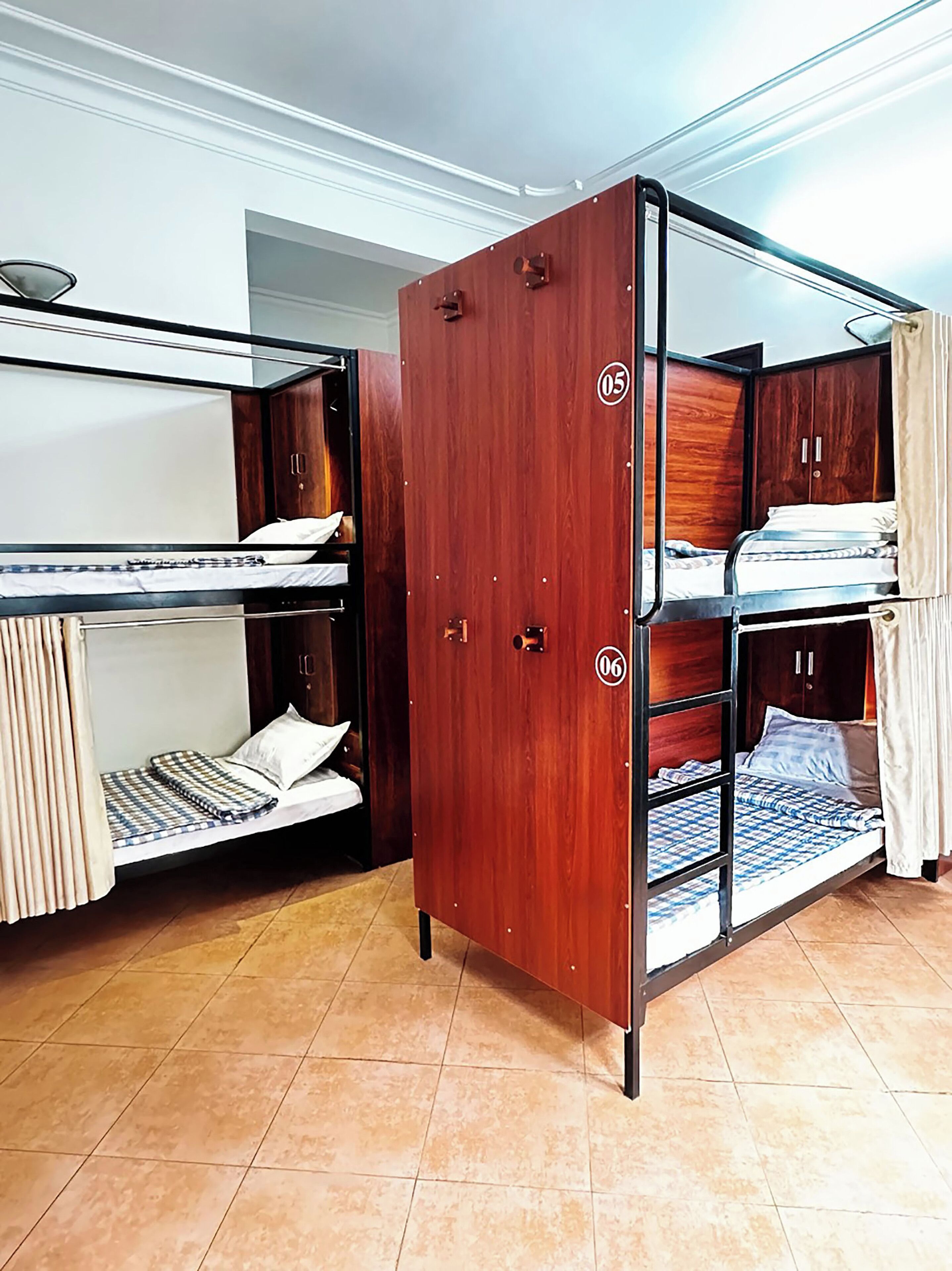 A dormitory room with bunk beds, a wardrobe, and a tiled floor.