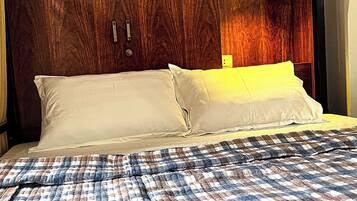 A bed with a plaid bedspread, a wooden headboard with frosted glass panels, and white pillows.