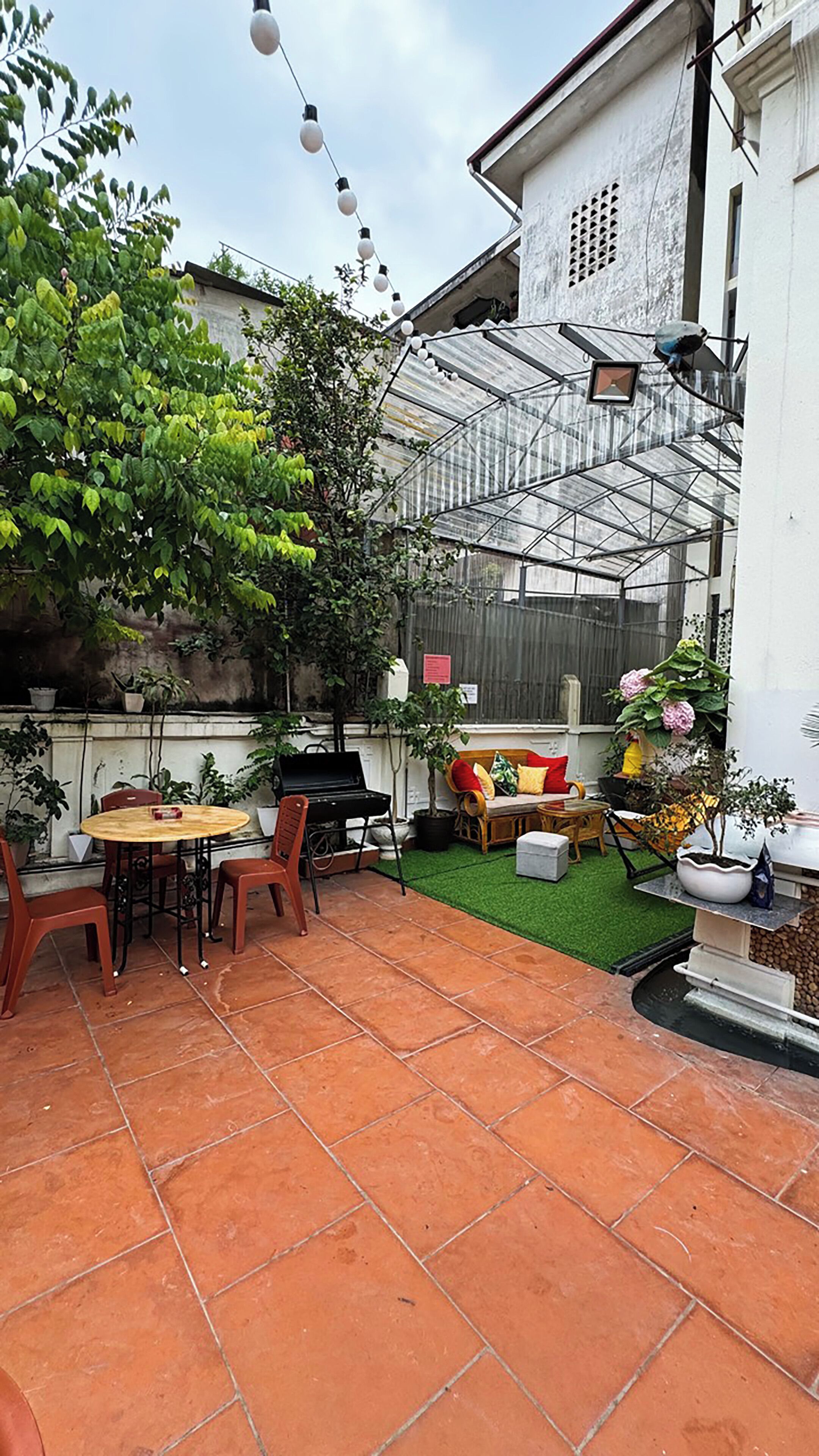 A patio area with a grill, outdoor seating, and potted plants.
