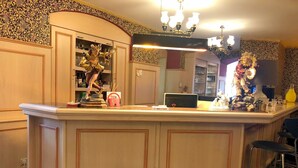 A bar area with a counter, bar stools, and a decorative statue. - Hotel Eulenspiegel (Riesa)