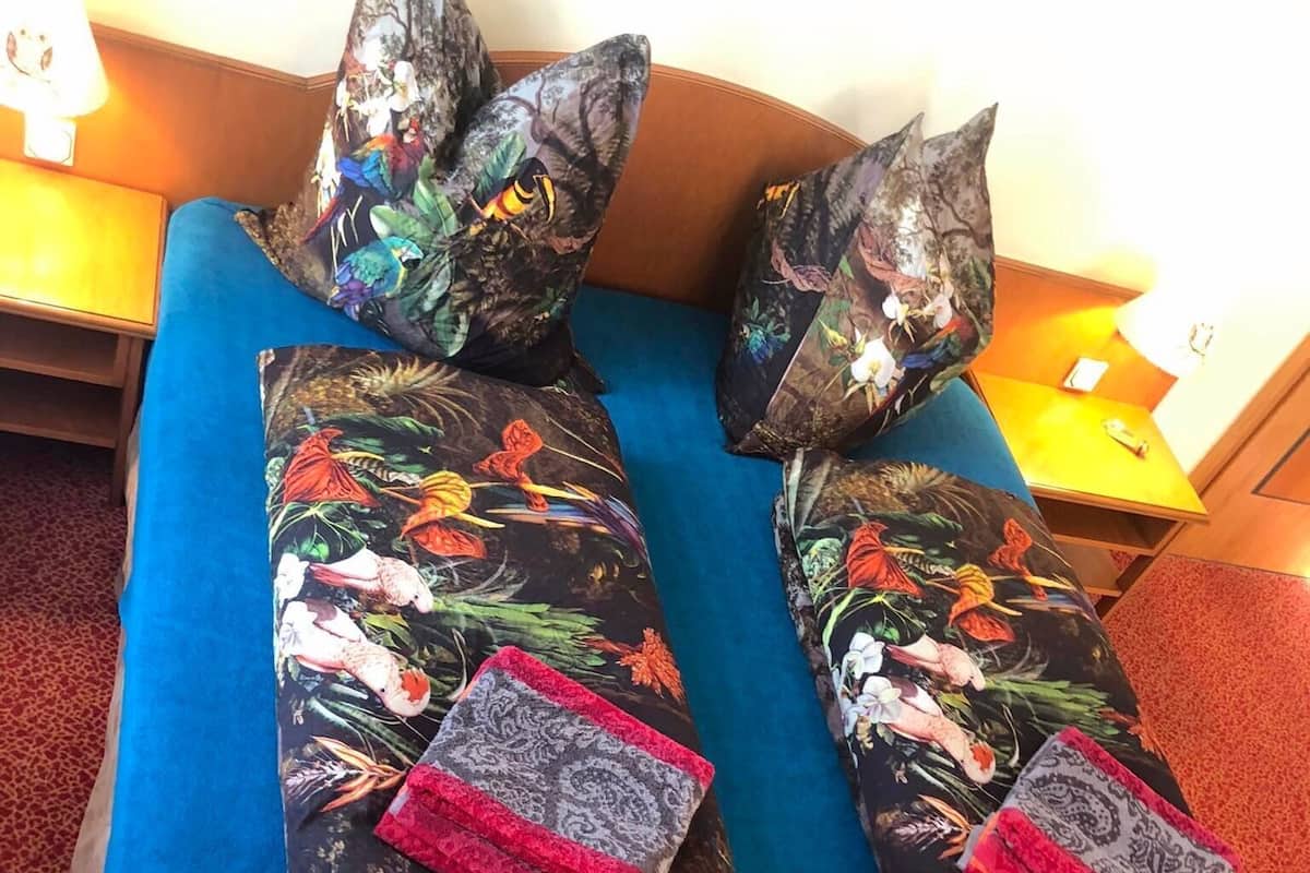 Una cama con almohadas estampadas con motivos florales y un edredón azul.