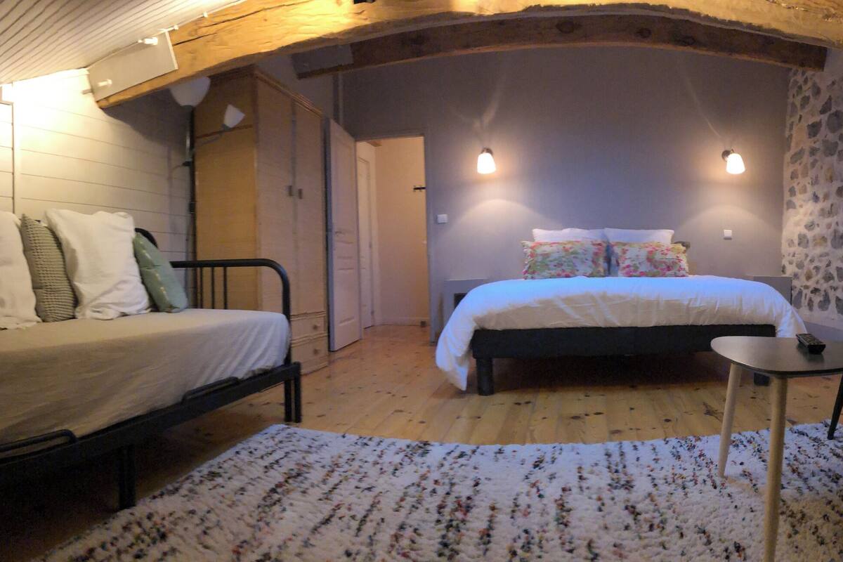 Un dormitorio acogedor en el ático con una cama, un sofá y una pequeña mesa.