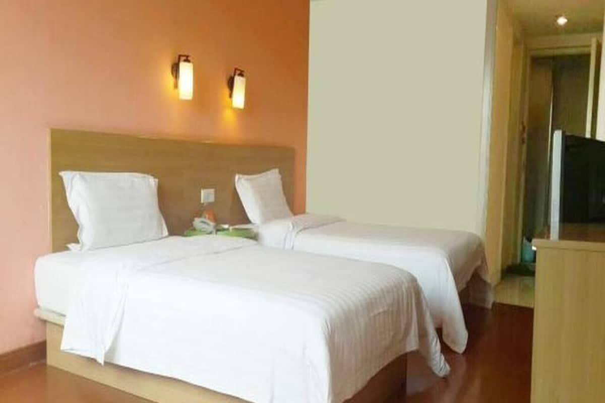 A hotel room with two beds, a wooden headboard, a nightstand, and a television.