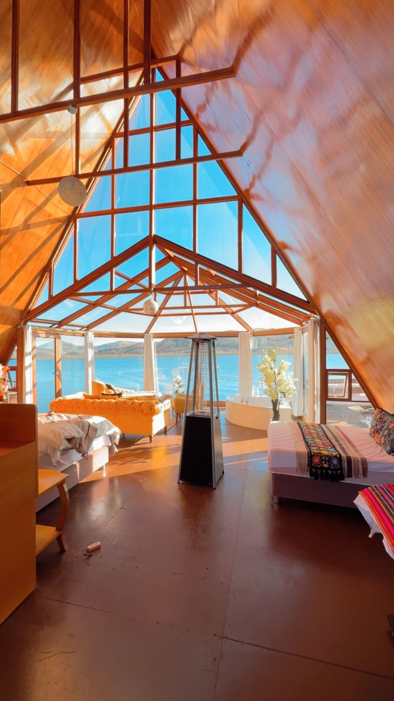 Een ruime kamer met een hoge nok, grote ramen en uitzicht op zee.