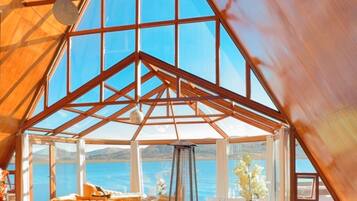 A spacious room with a high ceiling, large windows, and a view of the sea.
