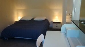 Une petite chambre à coucher, bien rangée, avec un lit, des tables de chevet et un banc.