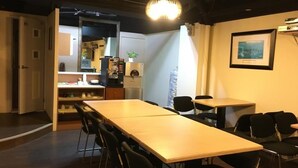 Uma sala de conferências com uma mesa comprida e cadeiras, uma área de kitchenette e um quadro pendurado na parede.