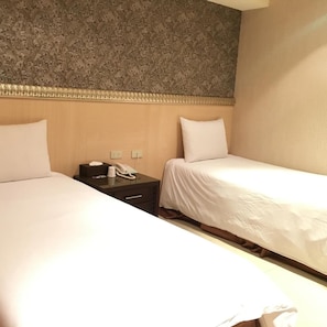 A hotel room with two beds, a bedside table with a phone, and a wall with a floral pattern. - Daylight Hotel (New Taipei City)