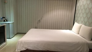 Quarto de hotel com cama, escrivaninha e cortina.