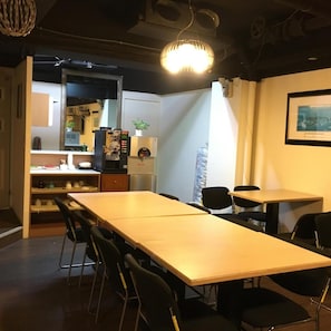 A conference room with a long table, chairs, a coffee machine, and a plant. - Daylight Hotel (New Taipei City)