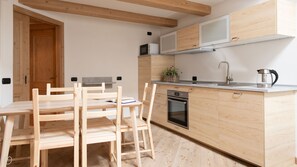 Eine moderne Küche mit Holzschränken, einem Einbauofen, einer Mikrowelle und einer Kaffeemaschine.