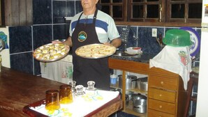 A kitchen with dark blue tiles, wooden cabinets, and a countertop with various kitchen items. - SITE REFUGIO DO RIO - BANANAL - SP (BANANAL)