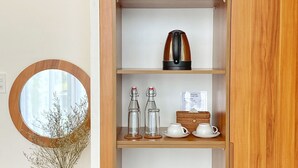 A wooden cabinet with shelves containing a vase, a kettle, and glass bottles. - Hoi An Cabbage Garden (Da Nang)