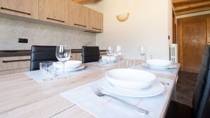 Un comedor con una mesa de madera dispuesta para cuatro personas, con platos, vasos y cubiertos.