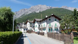 Una hilera de edificios tradicionales de estilo alpino con balcones, con montañas al fondo.