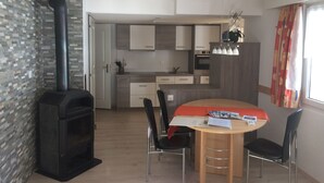 Una cocina moderna con armarios blancos, horno empotrado y estufa negra. Hay una mesa de comedor con cuatro sillas y mantel rojo.