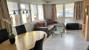 Una sala de estar moderna con un sofá, una mesa de centro de vidrio y una mesa de comedor con sillas.