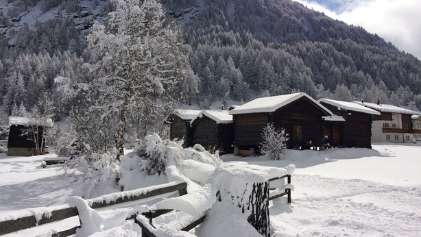 Una cabaña nevada con chozas de madera y un paisaje montañoso.