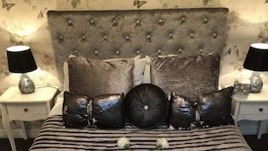 A bed with striped bedding, a tufted headboard, and two bedside tables with lamps. - Strontian Boutique Bed & Breakfast (Acharacle)