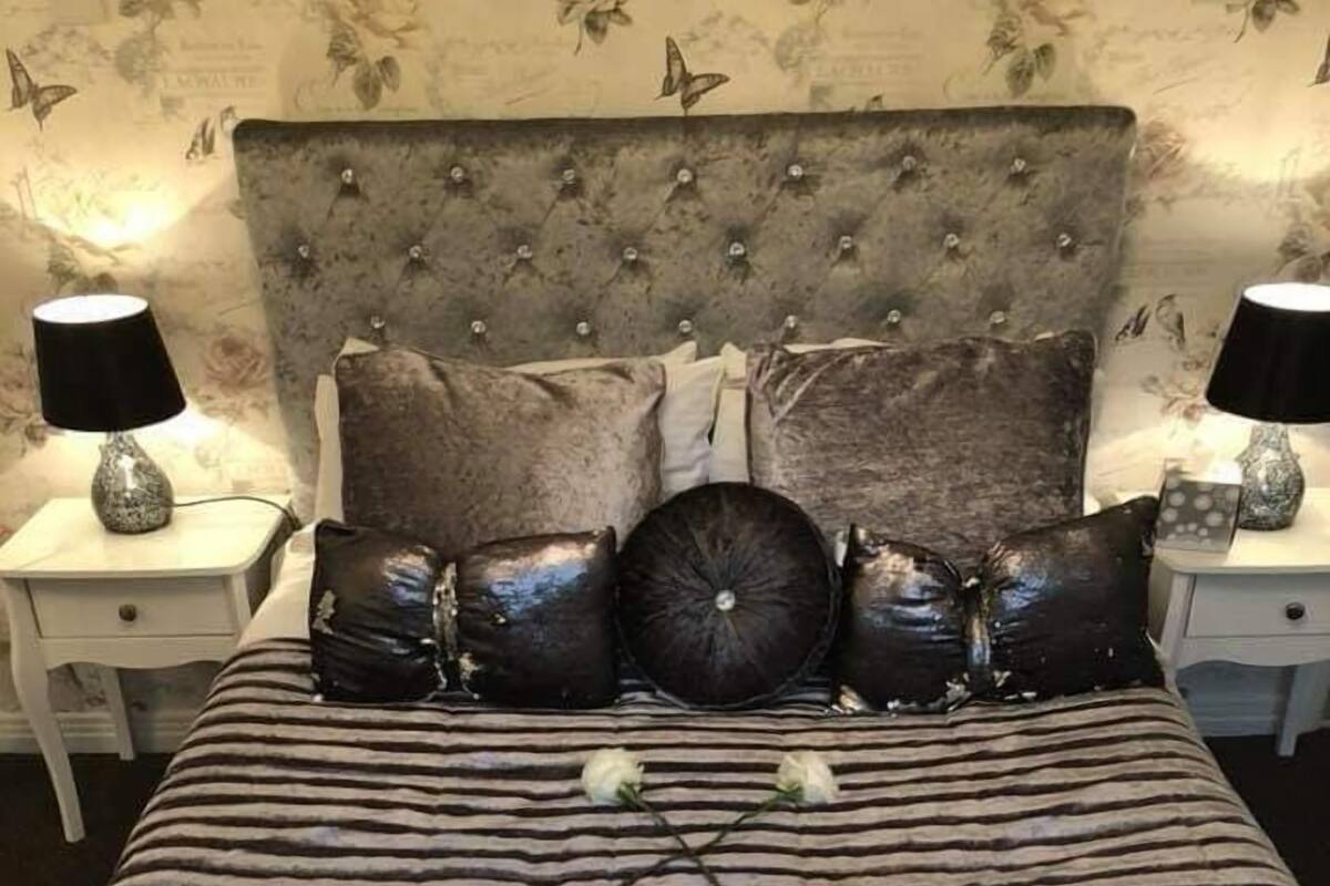 Una cama con ropa de cama a rayas, un cabecero capitonado y dos mesitas de noche con lámparas.