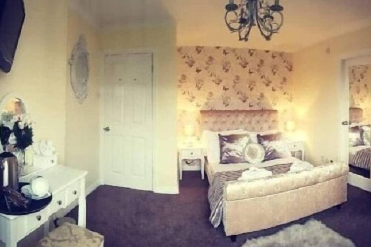 Un dormitorio con una cama grande, un aparador, una mesita de noche y un espejo.