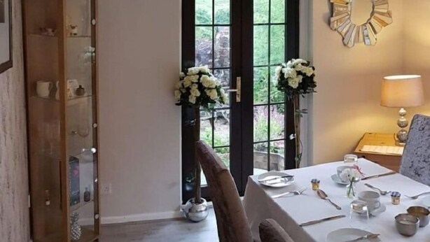 A dining area with a table set for four, a wooden cabinet, and a decorative mirror on the wall. - Strontian Boutique Bed & Breakfast (Acharacle)