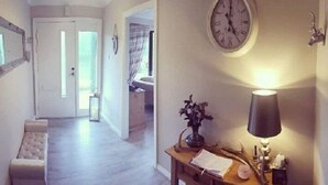 A hallway with a bench, a clock, a lamp, and a vase with flowers. - Strontian Boutique Bed & Breakfast (Acharacle)