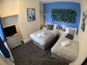 A hotel room with two beds, a TV, a painting, and a wall-mounted plant. - Whitworth Lodge. Sleeps 6 in 3 rooms netflix WIFI (Northampton)