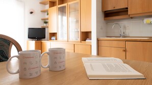 A kitchen with wooden cabinets, a television, and two Italianway mugs on a table with an open book. - San Giovanni 13/A - Foliage (Molina)