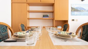A dining table set with plates, glasses, and cutlery, flanked by chairs with patterned cushions. - San Giovanni 13/A - Foliage (Molina)