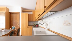 Una cocina moderna con armarios de madera, encimera blanca y un lavamanos.