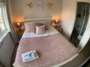 A bedroom with a large bed, two bedside lamps, a framed text on the wall, and a window with curtains. - Harpers Brook  5 bedrooms TV Netflix (Corby)