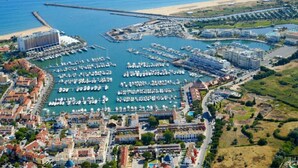 An aerial view of a coastal marina with multiple docks, a large hotel, and residential buildings. - ATTILA apartment by the sea (QUARTEIRA)