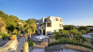 A Mediterranean-style villa with a patio, outdoor seating, and a staircase leading to the entrance. - Hotel Zaro (Forio)
