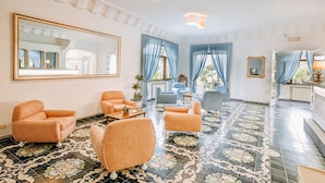 A spacious living room with a large mirror, blue curtains, and a patterned floor. - Hotel Zaro (Forio)