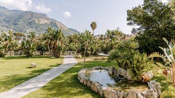Stroll through a tranquil garden surrounded by lush tropical plants and a serene mountain view.