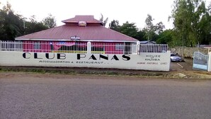 A Club Panas sign with a red building in the background. - Club Panas (Bondo)