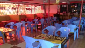 A restaurant with blue plastic chairs and tables, red walls, and a patterned floor. - Club Panas (Bondo)