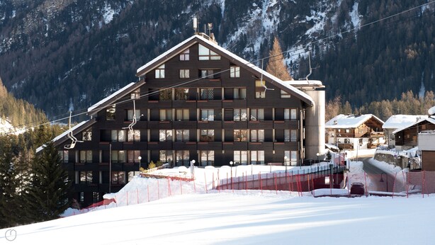A multi-story hotel with a ski lift in the background, surrounded by snow-covered mountains. - Plagheira 1 - Studio Apartment, Sleeps 2 (Valfurva)