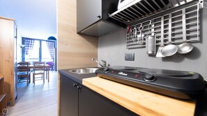 A modern kitchen with a black stove, stainless steel sink, and wooden countertop. - Plagheira 1 - Studio Apartment, Sleeps 2 (Valfurva)