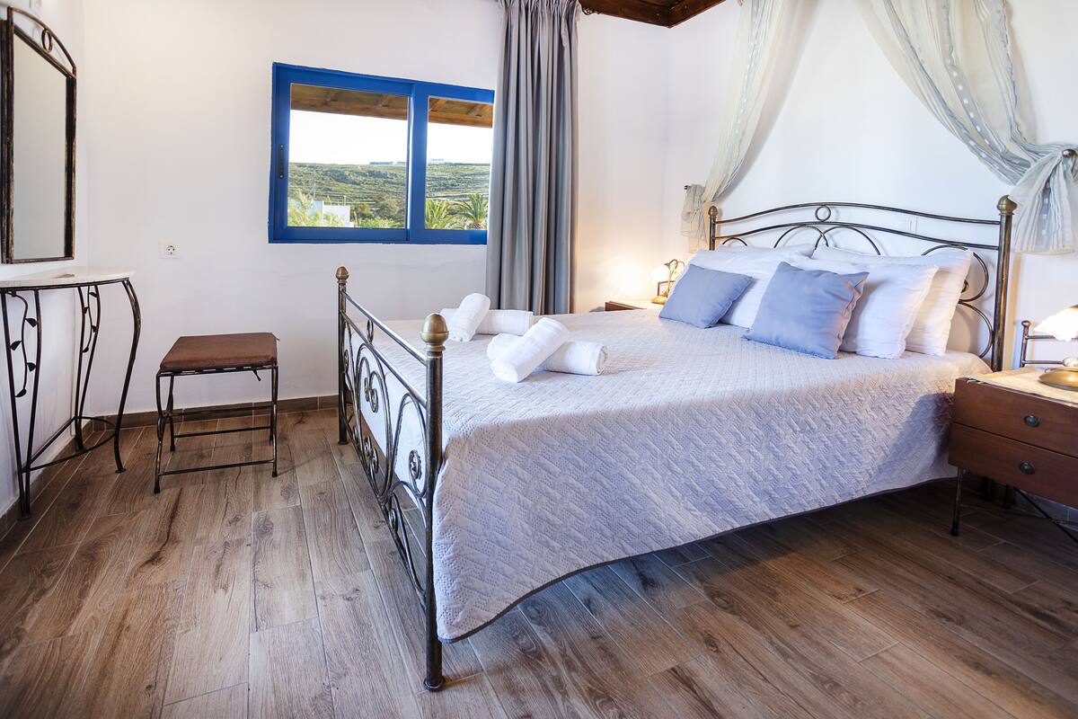 A bedroom with a bed, bedside table, and a window with a view.
