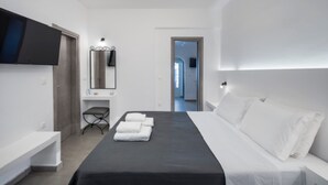 Una habitación de hotel moderna con cama, televisor en la pared, mesita de noche y espejo.
