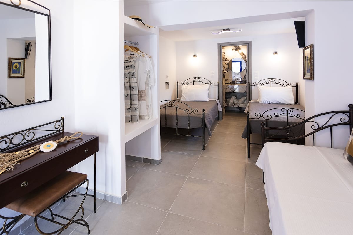 A bedroom with two beds, a dresser, and a mirror.