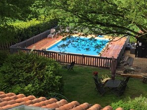Un jardin avec une terrasse en bois, une piscine et un espace clôturé.