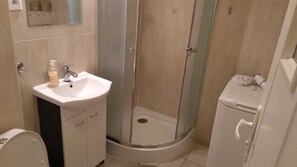 Ein Badezimmer mit einem weißen Waschbecken, einer Duschkabine aus Glas und einer Toilette.