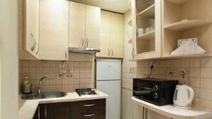 A compact kitchen with a sink, stove, microwave, and a small refrigerator. - Apartamenty Varsovie Zelazna (Warsaw)
