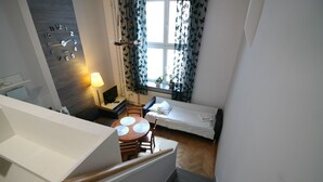 A bedroom with a bed, a desk, a chair, a lamp, and a wall clock. - Apartamenty Varsovie Zelazna (Warsaw)