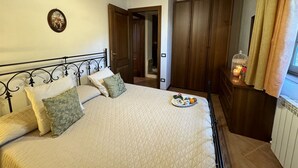 Un dormitorio con cama, armario de madera y mesita de noche con vela y bandeja de desayuno.